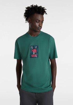 Green cotton t-shirt with a crew neck, featuring a rectangular graphic design with colorful motifs and "VANS" text at the center.