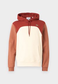 Sudadera con capucha de color crema y mangas rojo-marrón. Cuenta con un bolsillo tipo canguro, capucha con cordón y un pequeño logo en el pecho.
