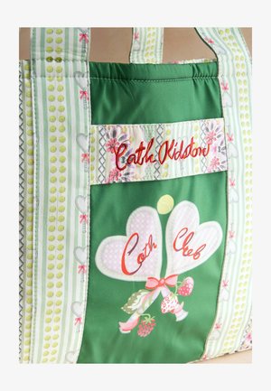 Grüne Stofftasche mit Blumen- und Herzmustern, "Cath Kidston" in Rot gestickt und zwei herzförmigen Luftballons mit dem Text "Cath Club".