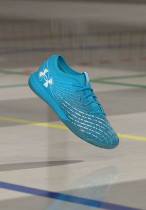 Turquoise athletic shoe with a textured upper, featuring a white logo and dynamic pattern, designed for agility and traction on indoor surfaces.