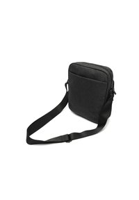 Črna tkaninska torba za pošto z zadrgo, ravno zasnovo, nastavljivim trakom in sprednjim žepom. Tekstura površine z minimalno kovinsko opremo.