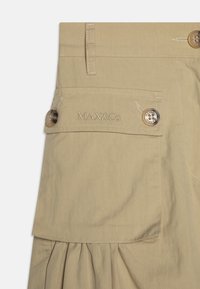 Beige skjørt med folder, med to knapper og en lommeklaff. "MAX&Co." broderet på livet. Glatt bomullmateriale.