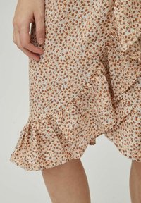 Bloemprint rok met een lichtbeige stof en kleine bruine en blauwe bloemen. Rimpelzoom voegt textuur en detail toe.