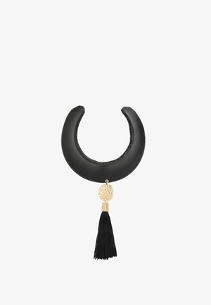 Czarny, pikowany półksiężycowy naszyjnik typu choker z pozłacanym, młotkowanym zawieszką i czarnym chwostem na białym tle.