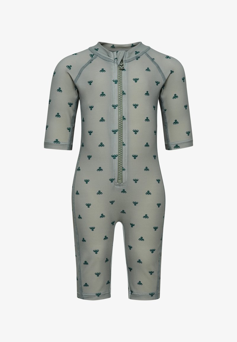 Combinaison grise à manches courtes pour bébé avec motif vert en forme de trèfle et fermeture éclair à l'avant allant du cou jusqu'au milieu du torse.