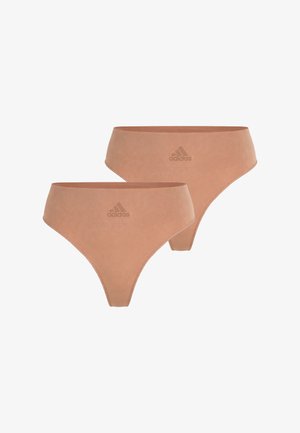 Kaksi saumattomasti valmistettua, ihonväristä naisten Adidas-alusvaatetta, joissa on korkeat lahkeensuut ja logo keskitettynä etummahan vyötärönauhaan.