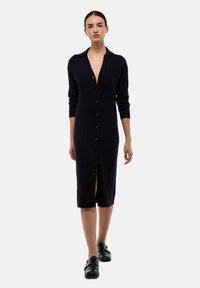 Robe en tricot noir à côtes avec manches longues, col et boutonnière : design mi-long avec une fente en bas.