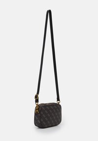 Liten rektangulär crossbody-väska med logo-tryck i mörkbrunt och tan, guldfärgad hårdvara och justerbar svart rem hängande mot vit bakgrund.