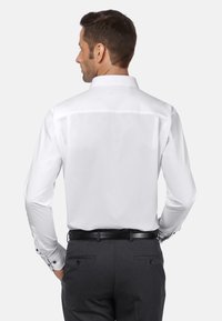 Witte shirt met lange mouwen, een klassieke kraag en knoopmanchetten. Gedetailleerd ontwerp van de achterkant; gladde, strakke stof.