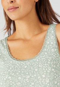 Canotta verde chiaro con un motivo floreale, scollatura ondulata e una consistenza morbida, progettata per un fit confortevole.