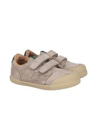 Zapatillas de ante beige con suela de goma, dos correas de velcro y un acento verde en el talón. Cuentan con orificios de ventilación en los lados.