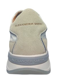 Weißer Sneaker mit einem beigen Veloursleder-Fersenbereich, blauen Akzenten, grauer Laufsohle und "ALEXANDER SMITH"-Branding an der Ferse und der Seite.