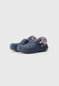 Blå slip-on klipklapper med ventilationshuller og blødt gråt fuzzy for, let vinklede til venstre på en hvid baggrund.