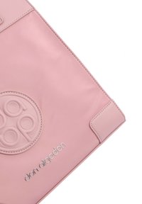 Bolso de hombro sintético rosa con un logo circular texturizado, marca en plata y acabado suave con un diseño minimalista.