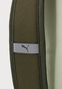 Groene stoffen rugzak met zwarte biezen; bevat een grijze Puma-logo patch. Textuur van de buitenkant met een gladde voering aan de binnenkant.