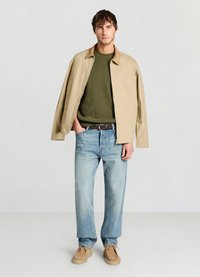 Veste beige légère, pull en tricot vert, jean bleu clair et chaussures style mocassin couleur fauve. Design simple avec une coupe décontractée et des détails minimalistes.
