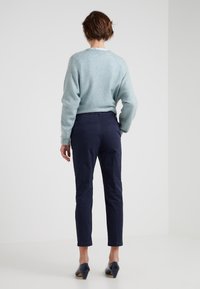 Maglione azzurro chiaro e strutturato con scollo a girocollo, abbinato a pantaloni eleganti blu scuro con una vestibilità slim e taglio alla caviglia.