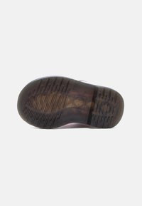 Σόλα μαύρου παπουτσιού με υφή λαβής και ανάγλυφο λογότυπο σταυρού στο κέντρο, εμφανιζόμενη σε λευκό φόντο.