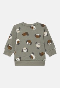 Felpa grigia con texture a cialda, caratterizzata da un motivo giocoso di cani in marrone, nero e bianco. Girocollo e polsini a coste. Tessuto morbido.