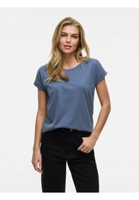 Blå bomulls-t-shirt med upprullade korta ärmar och rund halsringning, i kombination med svarta jeans. Slät textur, avslappnad passform.