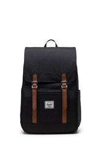 Black fabric backpack with brown leather straps, flap closure, and front logo patch; rectangular shape with adjustable shoulder straps.