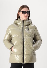 Casaco acolchoado com capuz em verde oliva claro, com superfície brilhante e refletiva, fecho de correr completo e bolsos laterais. Inclui detalhes em preto.