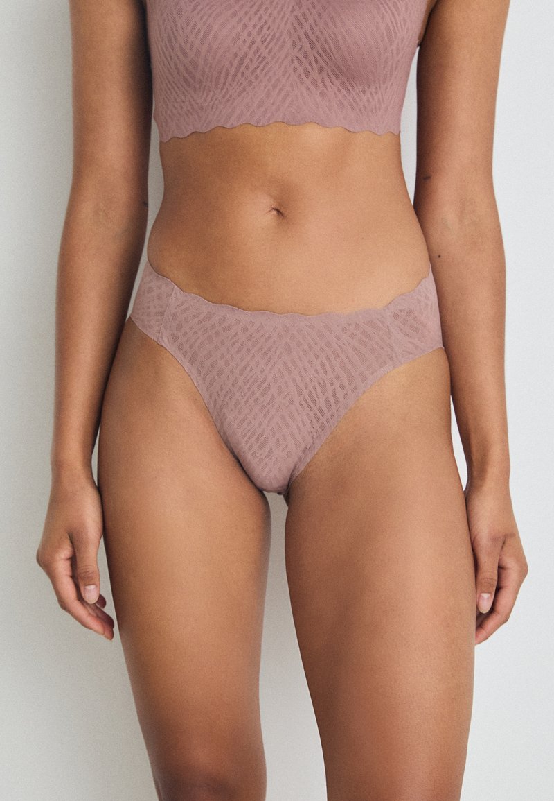 Mauve színű fehérnemű szett, amely texturált mintázattal, geometriai formákkal, ívelt szélekkel és sima, könnyű anyaggal rendelkezik.