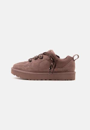 Brun ruskind lavskåret sneaker med tyk sål, runde mønstrede snørebånd, polstret krave og trækstrop ved hælen.