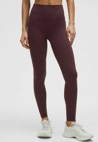 Maroonsed kõrge vöökoha leggingsid sileda tekstuuri ja lamedate õmblustega, koos heledate sportlike kingadega, mis sisaldavad võrkkatte aktsente.