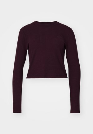 Top scurt cu mânecă lungă, de culoare burgundă, cu textură canalată, decolteu tip crew și logo subtil al brandului pe piept. Material moale și design ajustat.