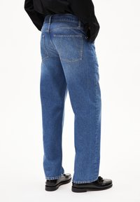 Jean en denim bleu clair avec une coupe décontractée, design à cinq poches et détails de couture. Fini avec une texture légèrement décolorée et des jambes droites.