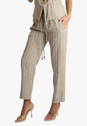 Pantaloni in lino beige a righe con coulisse frontale e tasche, indossati con sandali trasparenti con tacco alto.