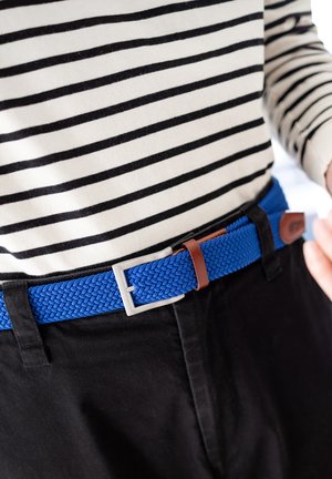 Geweven blauwe riem met een zilveren gesp en een bruin leren accent, gedragen bij een zwart gestreept longsleeve shirt en zwarte broek.