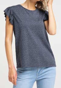 Mörkblå kortärmad topp med volangdetaljer och vitt prickmönster, gjord av mjukt tyg, med rund hals och lös passform.