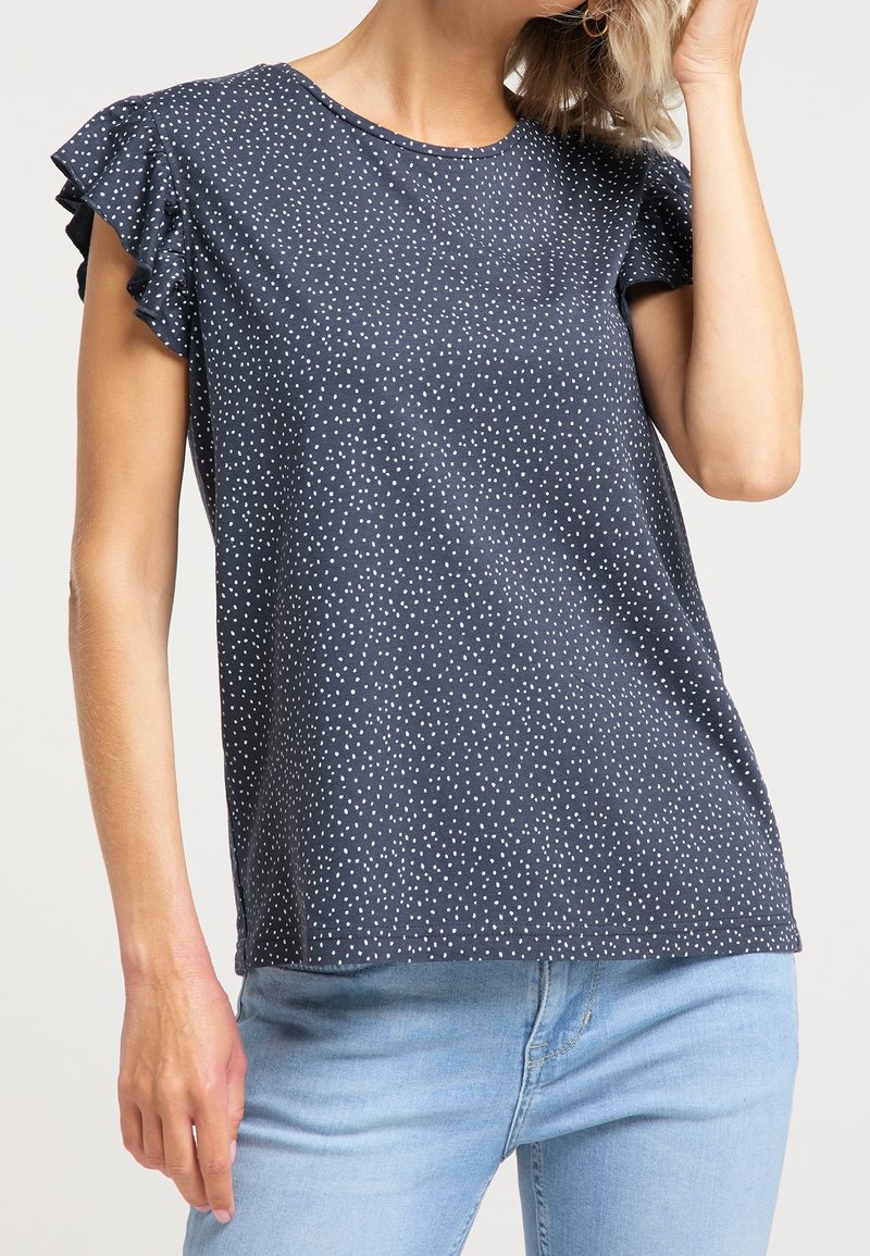 Mörkblå kortärmad topp med volangdetaljer och vitt prickmönster, gjord av mjukt tyg, med rund hals och lös passform.