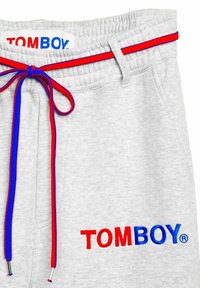Grijze sweatpants van een katoenmix, met een rode en blauwe trekkoord, en het "TOMBOY" logo in rode en blauwe borduring op het been.