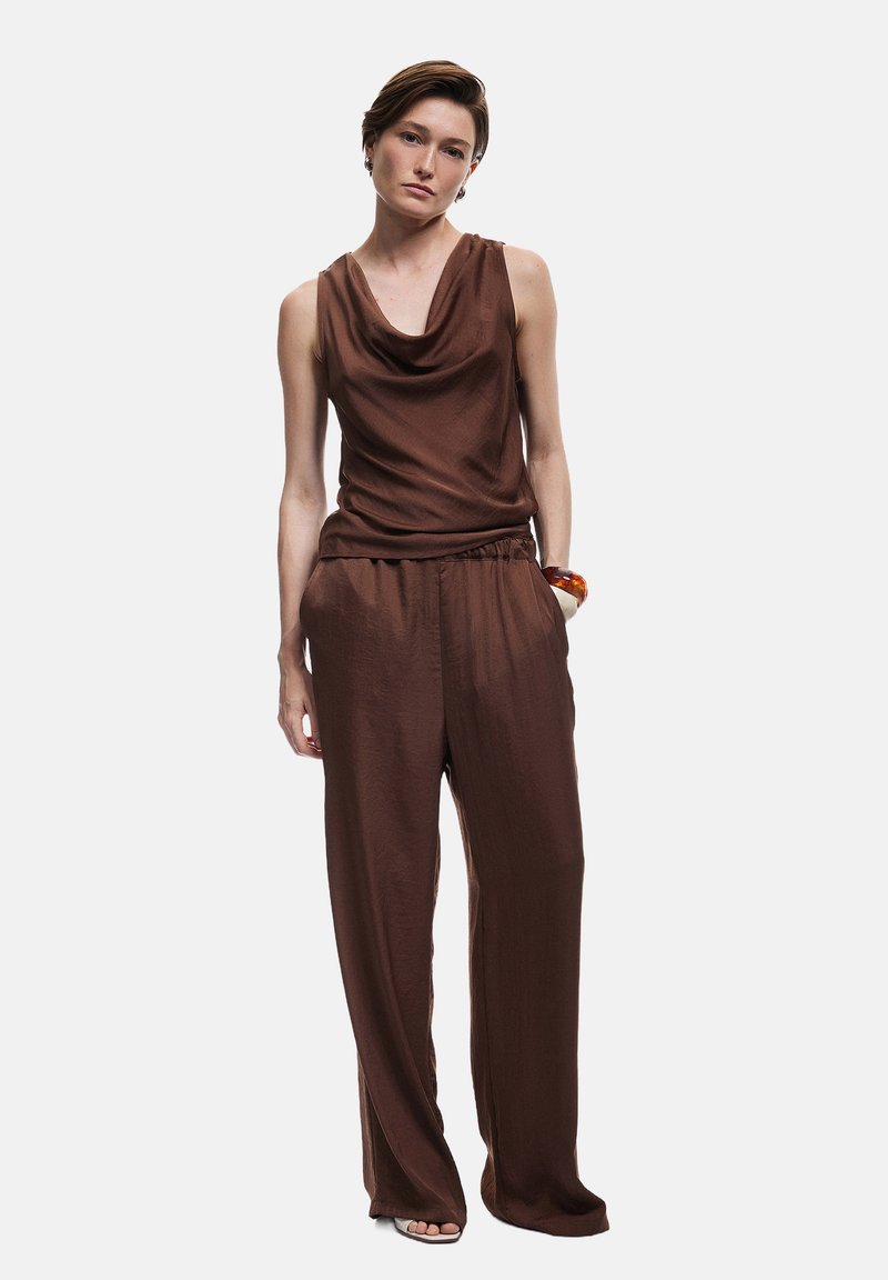 Top marrón sin mangas con escote drapeado, combinado con pantalones holgados a juego. Textura suave, piernas amplias y cinturilla elástica.