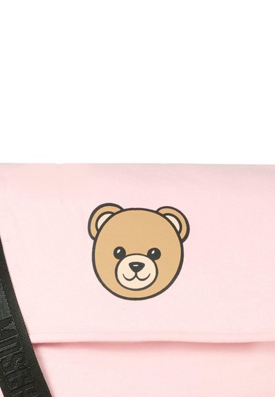 Lyserød skuldertaske i stof med et bjørnehoved i brun med sorte konturer og en tekstureret sort strop med logodetalje.