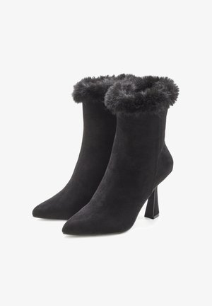 Black suede ankle boots with a pointed toe and a fur trim at the top, featuring a sturdy block heel for added support.