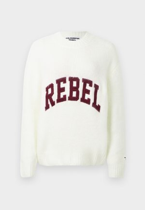 Valkoinen neulepaita, jossa on ribbineulekaulus, hihansuut ja helma. Paidassa on suuri maroon-värinen "REBEL" -teksti rinnassa.