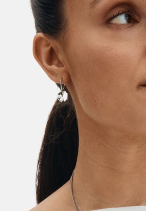 Hõbedast rõngaskõrvarõngas südamekujuga ripatsiga. Ripats on läikiva viimistlusega ja peegeldava pinnaga. Lihtne ja kaasaegne disain.