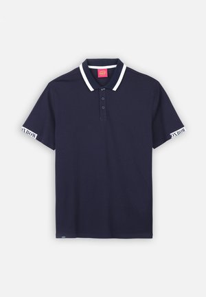 Polo bleu marine avec un col blanc et des accents de manches blancs. Comprend une patte de boutonnage à trois boutons et un logo sur la manche gauche. Fait en matériau en coton doux.