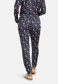 Tengerészkék pizsamakészlet, melyre hóemberek, fák és ünnepi motívumok mintázata van nyomtatva. Puha anyagból készült, rugalmas derékpánttal és szűkülő szárakkal.