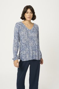 Blouse à manches longues à motifs bleus avec un col en V et une coupe décontractée. Le tissu présente un délicat motif floral en blanc. Assortie avec un pantalon marine.