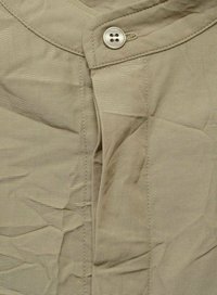 Camicia khaki con bottoni realizzata in un tessuto liscio e testurizzato, con colletto a V e chiusura a quattro bottoni con un leggero dettaglio di pieghe.
