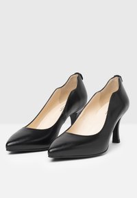 Talons en cuir noir avec des pointes effilées, côtés bas et talons carrés de 7 cm ; texture lisse et design minimaliste.