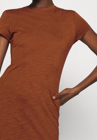 Kahvinruskea, istuva mekko, jossa on lyhyet hihat, pyöreä pääntie ja tasku sivussa; valmistettu pehmeästä, tekstuurisesta kankaasta.