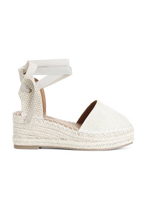 Sandalo con zeppa espadrille in beige con tomaia in tessuto testurizzato, suola in juta intrecciata e lacci alla caviglia in raso. Punta arrotondata e soletta imbottita.