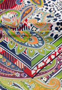 Multicolored patterned fabric featuring paisley, geometric, and floral designs in blue, red, green, yellow, and white with a smooth texture.
