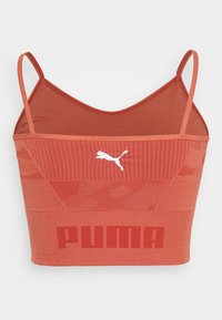 Rød sportsbh med tynde stropper, der har teksturerede mønstre, et solidt bånd og fed "PUMA" branding i kontrastfarve på fronten.